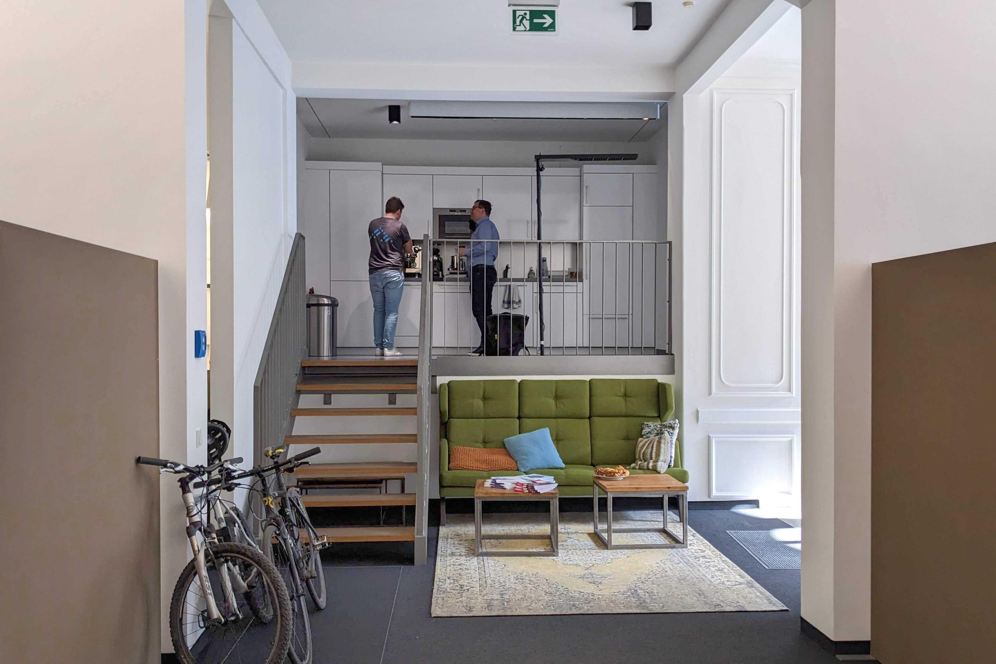 2 Personen, die sich in einer höher gelegenen Küche im Office Hamburg unterhalten.