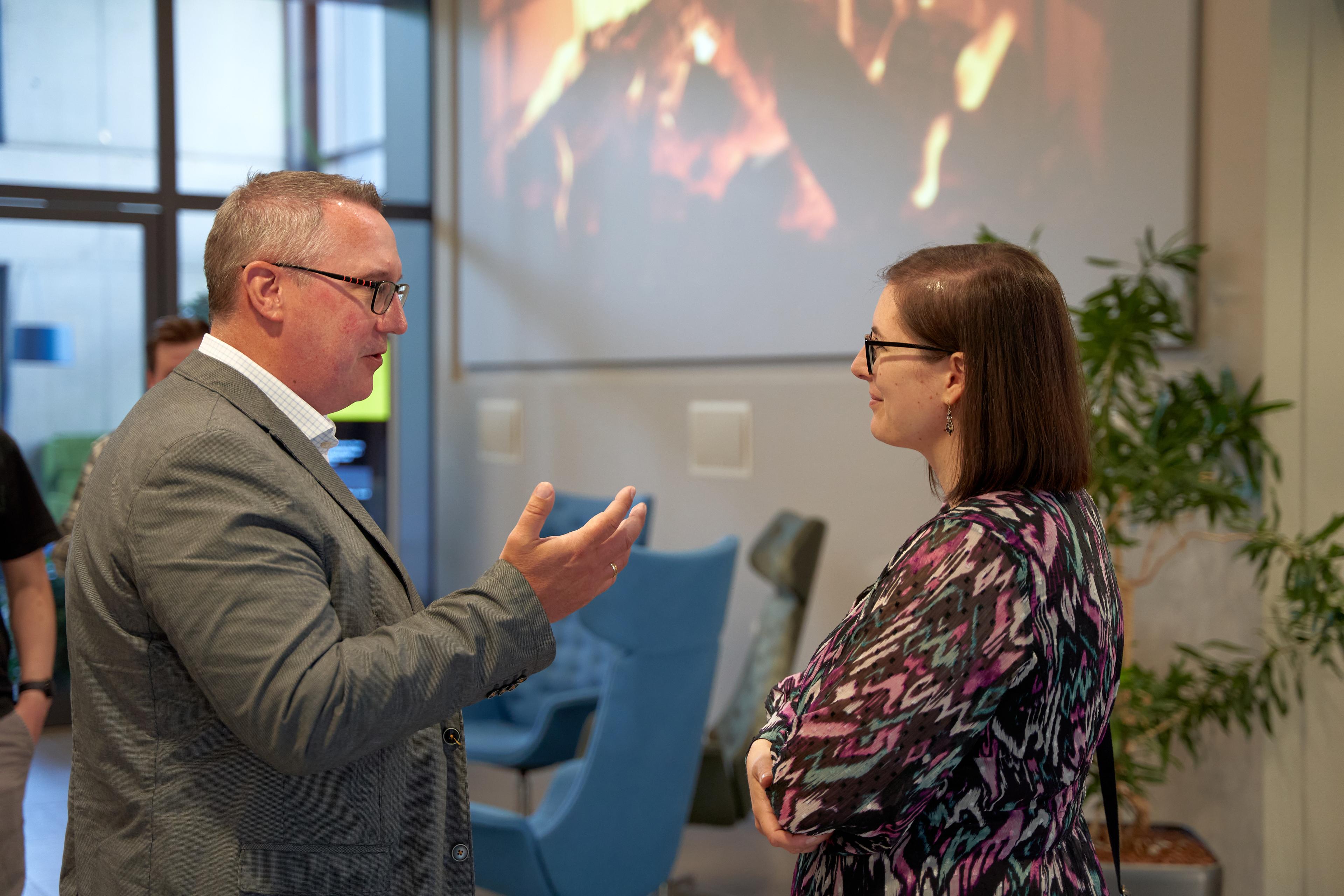 2 Personen die miteinander Reden im Auditorium der codecentric AG, im Hintergrund ein and die Wand projektiertes Lagerfeuer.